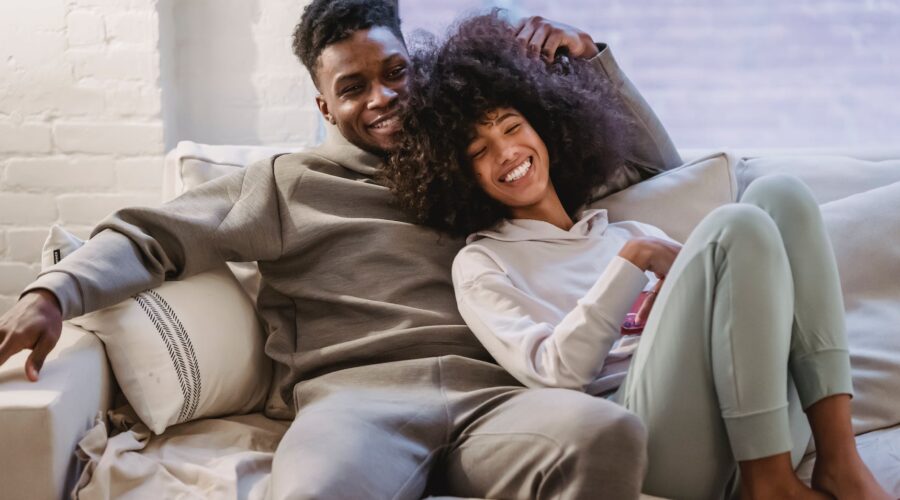 beloved african american couple cuddling and smiling on couch